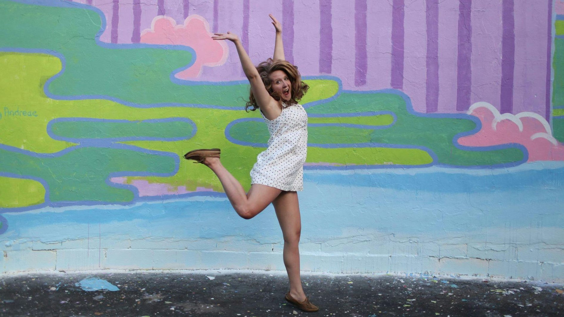 a happy girl jumping in from of the mural
